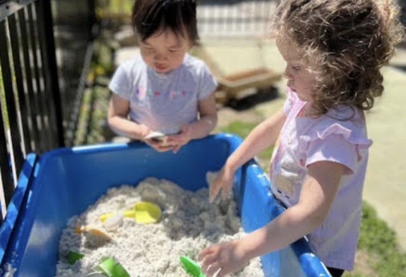 two students playing in a sandbox