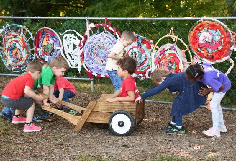 students pushing another student in a cart on the playground