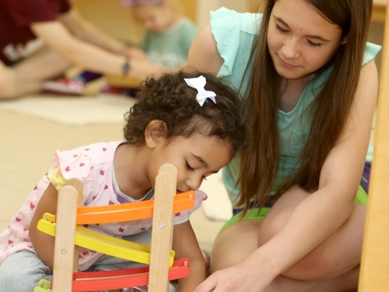 teacher and toddler student using a wooden toy